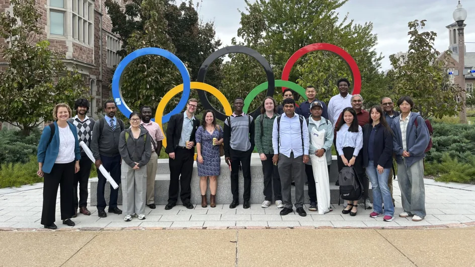 Nineteen attendees of ASA Day 2026 pose in front of the Olympic rings on WashU's Danforth Campus