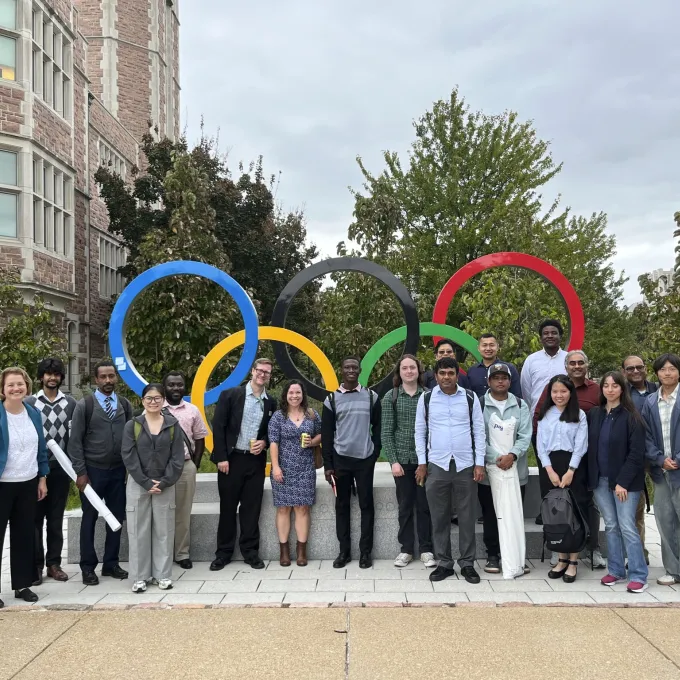 Nineteen attendees of ASA Day 2026 pose in front of the Olympic rings on WashU's Danforth Campus